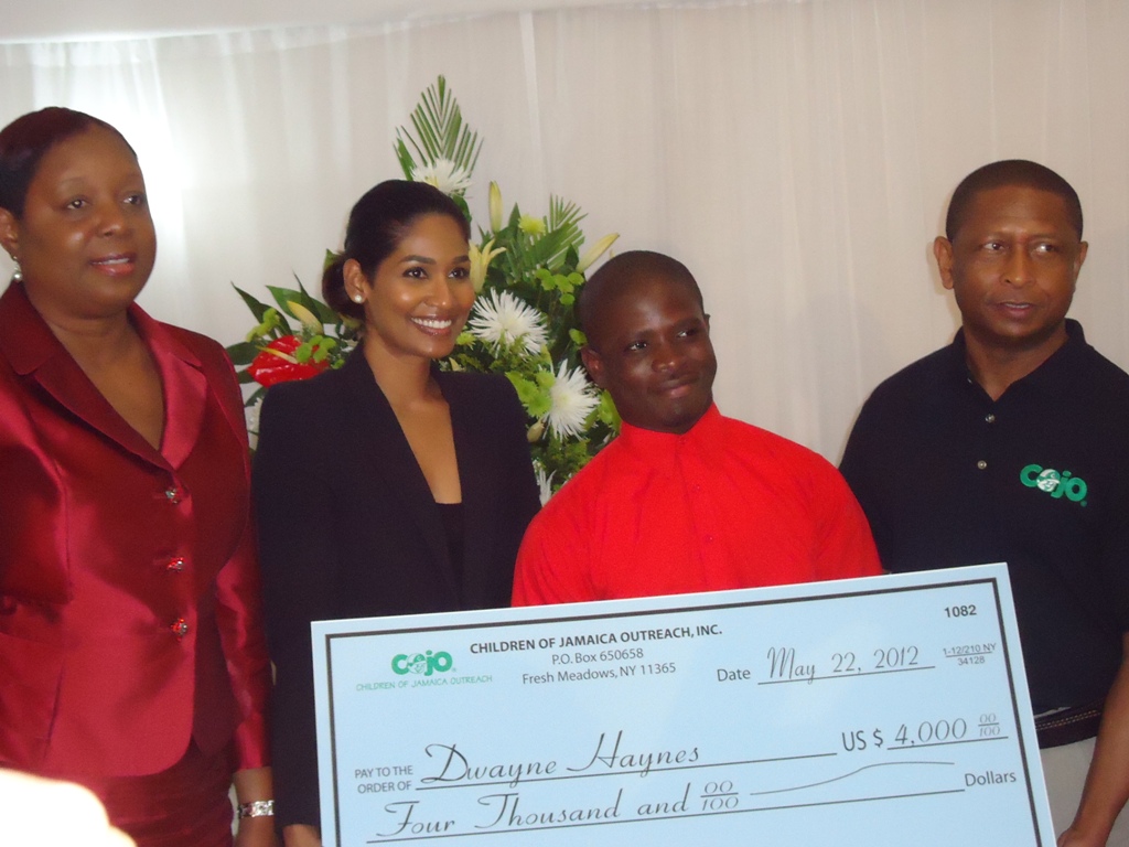 Former ward of the State Dwayne Haynes (second right) recently accepting scholarships from COJO.  From left, Minister of Youth and Culture the Hon. Lisa Hanna; Founder and President of Children Outreach of Jamaica Gary Williams.